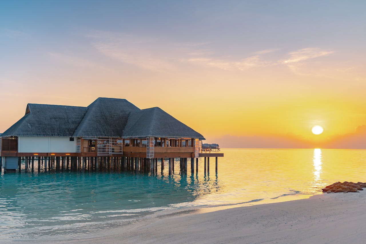 Luxury overwater bungalow with ocean view at sunrise, ideal for tropical travel and vacation.