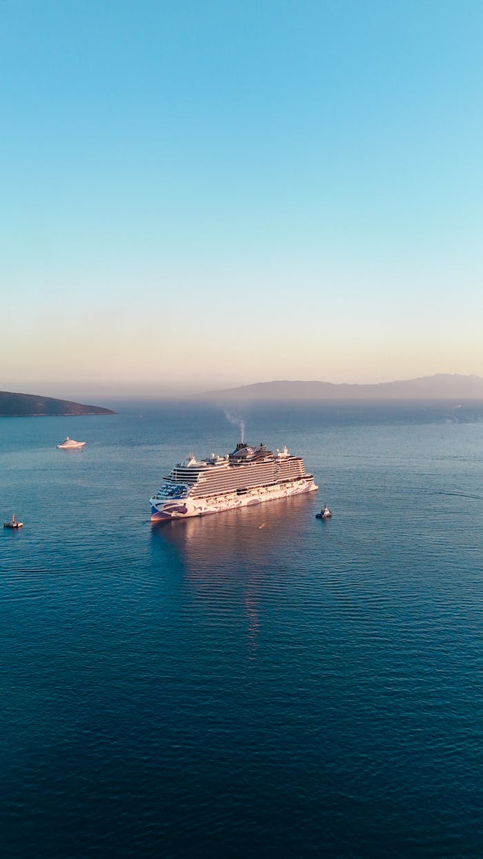 A luxury cruise ship sails serenely on open water during a vibrant sunset.