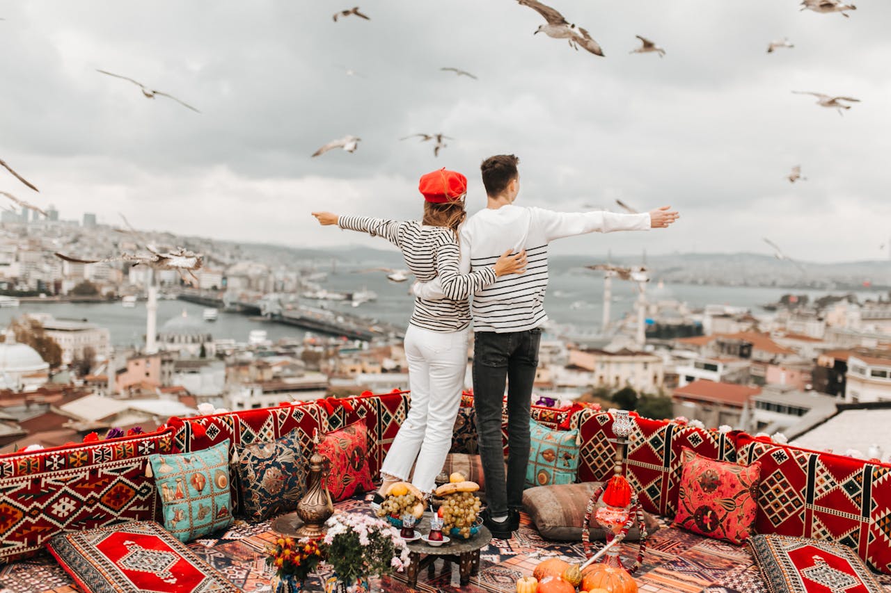 Couple embracing on a colorful Istanbul rooftop with seagulls and cityscape in the background.