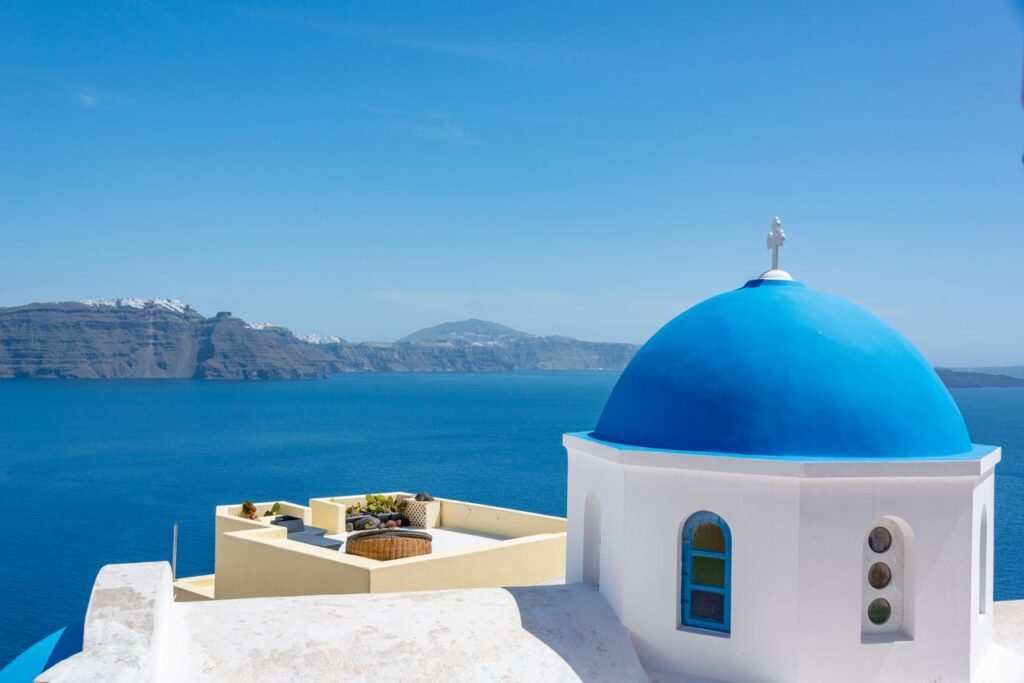How To Spend 7 Days in Greece (And What I'd Do Again) Iconic blue dome church in Santorini with a stunning view of the Aegean Sea.