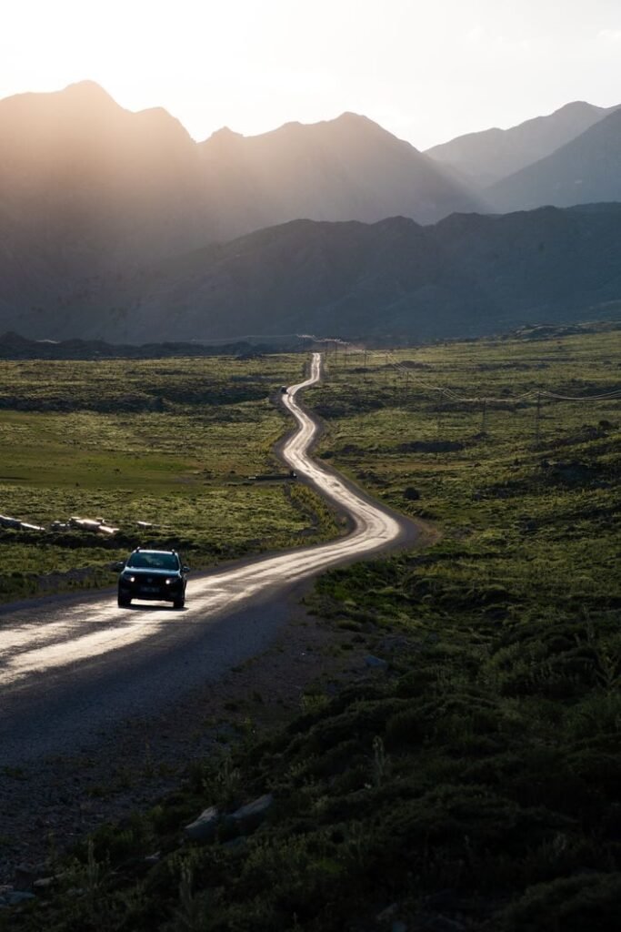 A serene road winding through a mountainous landscape at sunset, perfect for travel inspiration.